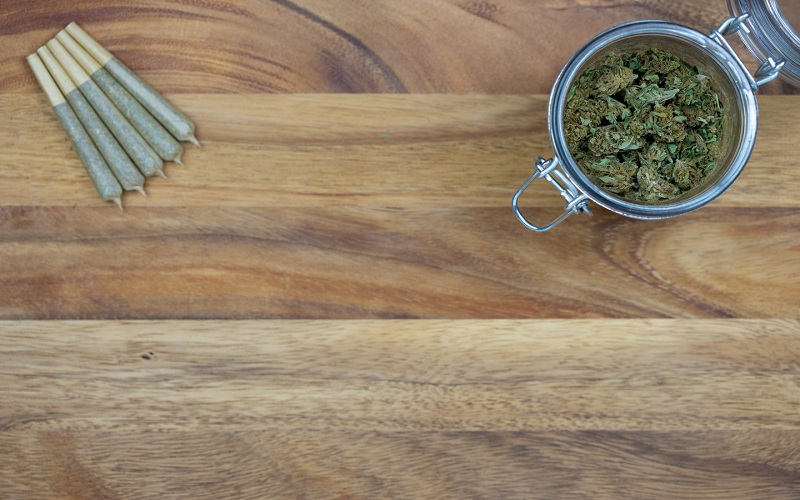 Cone shaped joints with weed nugs in a glass jar on a wood surface